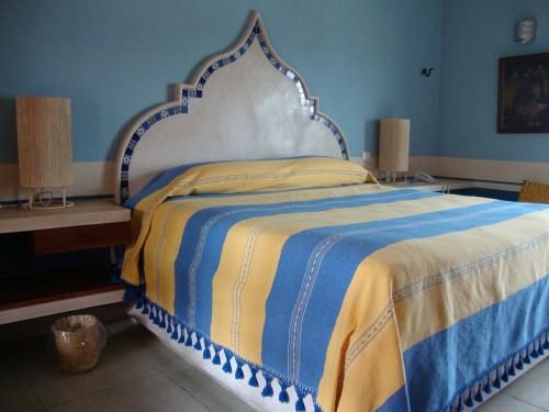 a bedroom with a bed with a blue and yellow blanket at Hotel Boutique Casa San Angel in Mérida