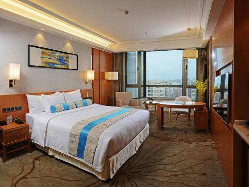 a hotel room with a large bed and a desk at Menshine Gloria Plaza Hotel in Shantou