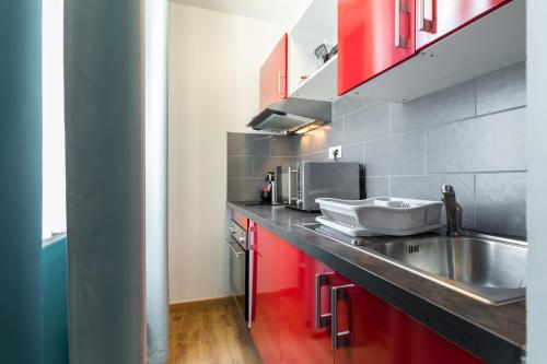 a kitchen with a stainless steel sink and red cabinets at Florella Clemenceau Apartment in Cannes