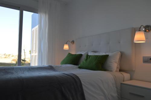 a bedroom with a bed with green pillows and a window at Hilly's Place in Roldán