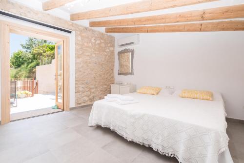 Dormitorio blanco con cama grande y puerta corredera de cristal en Can Diana, en Campanet
