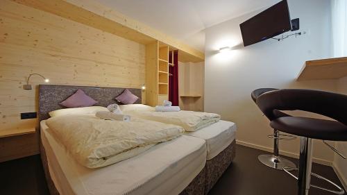 a bedroom with two beds and a chair in it at Alpin Relais B&B Villa Melisse in Colfosco