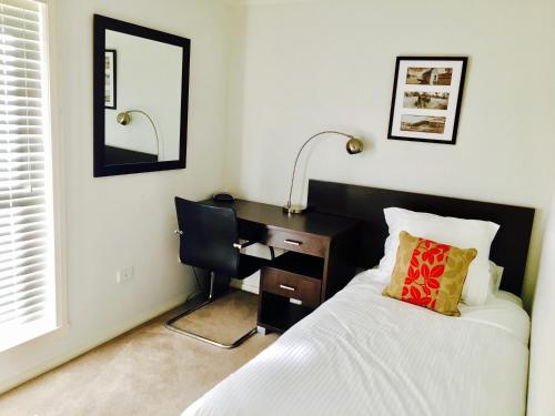 a bedroom with a bed, chair, lamp and a window at Encore Apartments in Bathurst