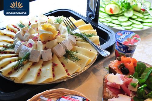 プシェムィシルにあるHotel Restauracja VILLA BOLESTRASZYCE- PRZEMYŚLのチーズとその他の食べ物が載った2つのトレイが置かれたテーブル