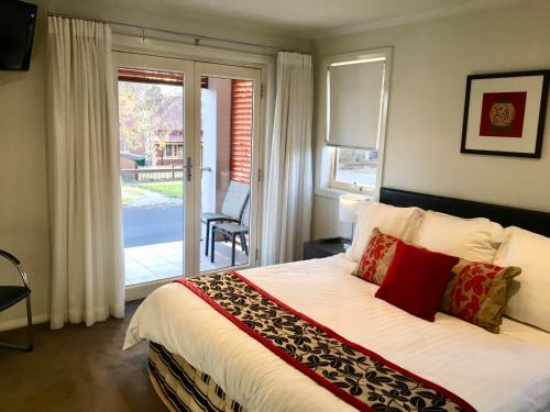 Un dormitorio con una cama grande y una puerta corrediza de vidrio. en Encore Apartments, en Bathurst