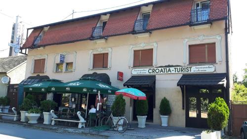 a store with green umbrellas in front of a building at RESTORAN PRENOĆIŠTE CROATIA TURIST in Ðakovo