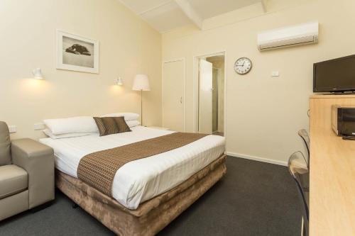 a hotel room with a bed and a tv at The Club Motel and Apartments in Wagga Wagga