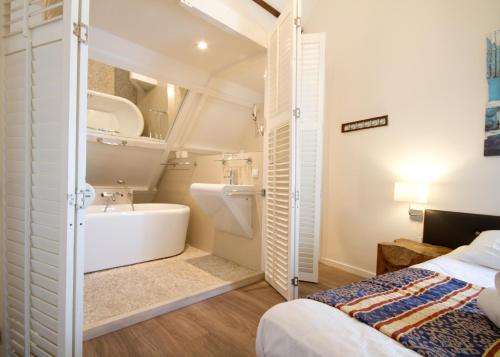 uma casa de banho com uma cama, uma banheira e um lavatório. em Acostar Hotel em Amesterdão