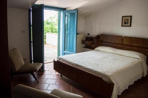 PietraperziaにあるCasa Fondachelloのベッドルーム1室(ベッド1台、椅子、ガラスのスライドドア付)