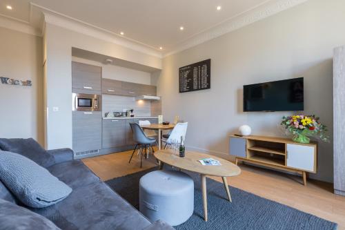 a living room with a couch and a table and a kitchen at Florella Jean Jaures Apartment in Cannes