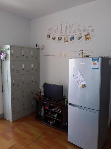 kuchnia z białą lodówką i telewizorem w obiekcie Makerhouse Hostel w mieście Hefei