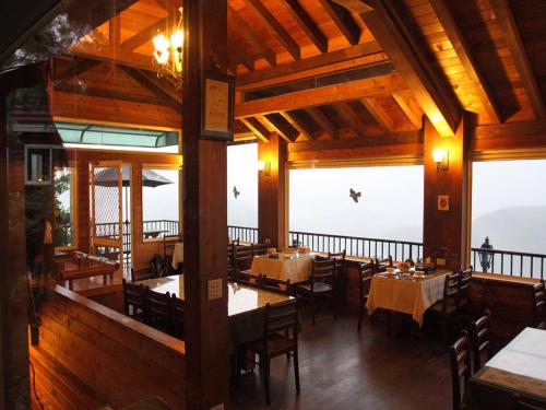un comedor con mesas, sillas y ventanas en 5 KM Villa en Renai