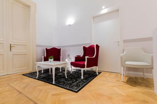 a living room with two red chairs and a table at Residenza Degli Artisti in Trieste