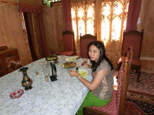 a woman sitting at a table eating food at Chicago Group of Houseboats in Srinagar
