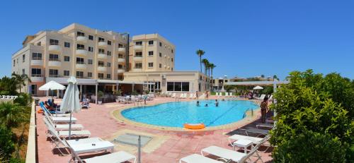 a swimming pool with lounge chairs and a hotel at Apartment nearby Golden Coast in Protaras