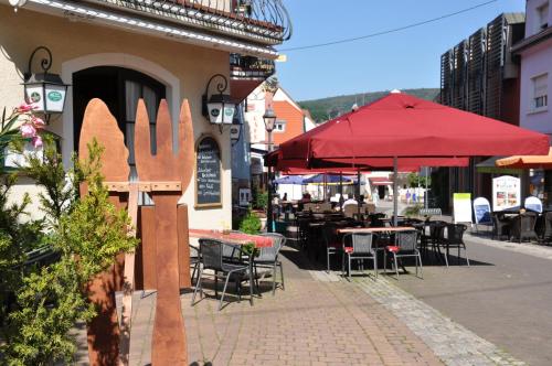 an outdoor patio with tables and chairs and red umbrellas at Hotel Restaurant Zum Schwan in Mettlach