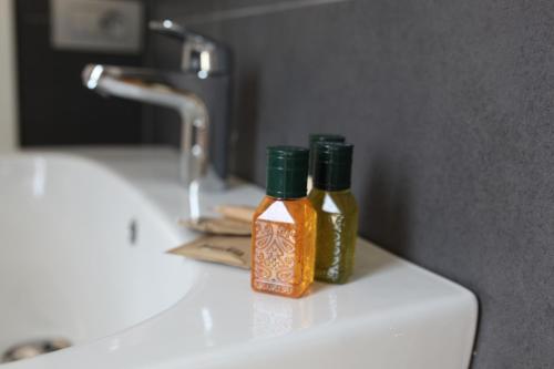dos botellas de mostaza sentadas en el lavabo del baño en SOHO Suite, en Fisciano