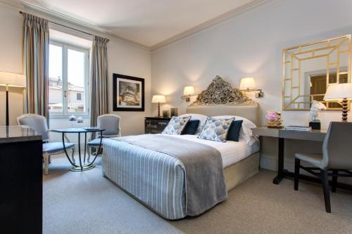 a hotel room with a large bed and a desk and a desk at Rocco Forte Hotel De Russie in Rome