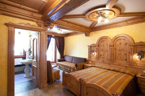 a bedroom with a large wooden bed and a bathroom at Hotel Le Ortensie in Roccaraso