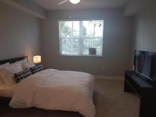 a bedroom with a bed and a tv and a window at Sawgrass in Sunrise