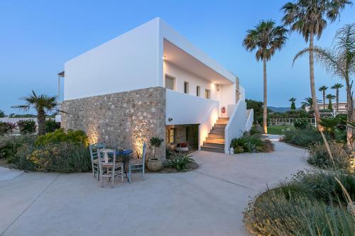 a house with a patio with chairs and palm trees at White Pearls-Adults Only Luxury Suites in Kos Town