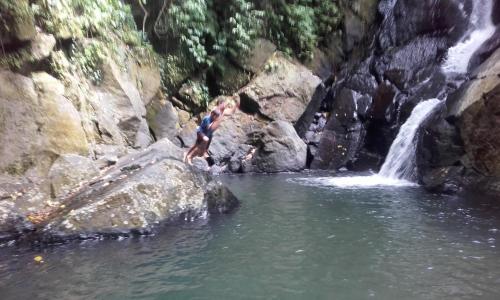 a person jumping off a rock into a waterfall at pulau weh sabang marifi in Paya