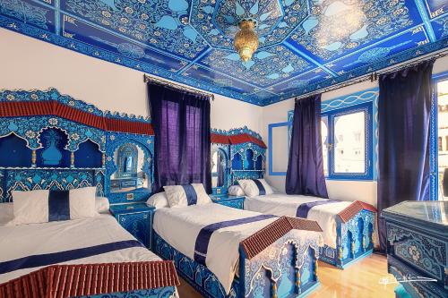 um quarto com 2 camas com tectos azuis e brancos em Hotel Madrid em Chefchaouen