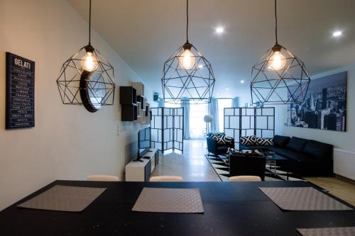 a living room with a table and two hanging lights at Apart Madryt in Tarnobrzeg