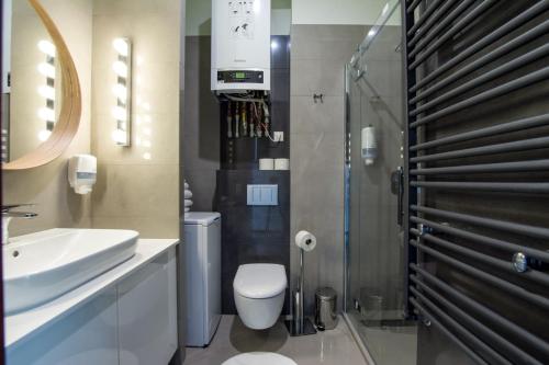 a bathroom with a toilet and a sink and a shower at Apart Madryt in Tarnobrzeg