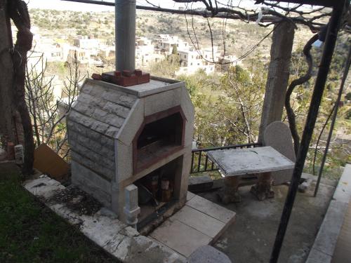 an outdoor fireplace with a table and a bench at Mresty Guest House in Al Mţullah