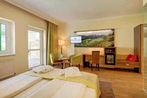 a bedroom with a bed and a table and a television at Hotel Schneeberghof in Puchberg am Schneeberg