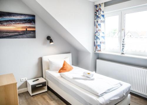 a small bedroom with a white bed with a window at Hotel Tum Stüürmann in Büsum