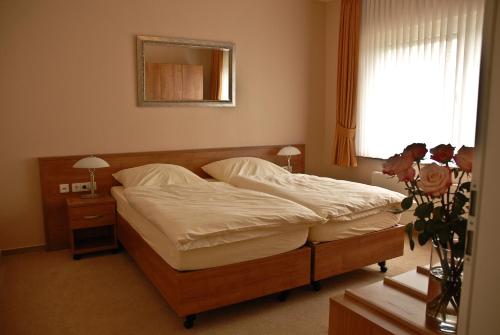 a bedroom with a bed and a vase with flowers at Land-gut-Hotel Restaurant Kreuz Meyer in Stuhr