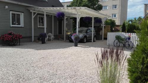 a house with a white pergola and a car at Haavalehe Summer House in Haapsalu