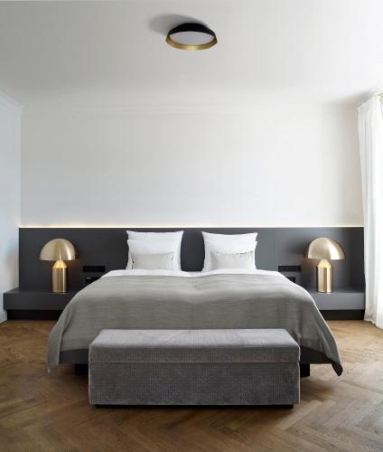 a white bedroom with a large bed and two lamps at Das Tegernsee in Tegernsee