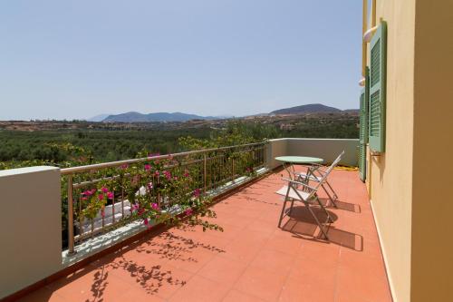 a balcony with a table and chairs and flowers at Athena Villas Olive Grove & Estate in Gouves