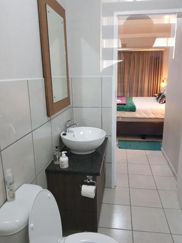 a bathroom with a sink and a toilet and a mirror at JS Inn in Nelspruit