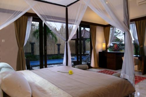 a bedroom with a large white bed with curtains at Villa Aamoda in Canggu