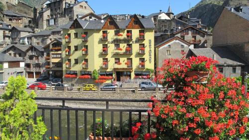 a building with red flowers in front of a city at Hotel De Rei in Llavorsí