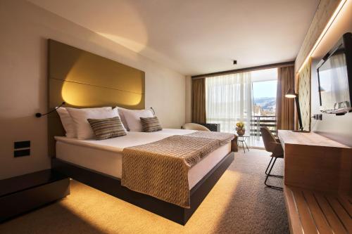 Cette chambre comprend un lit et une grande fenêtre. dans l'établissement Rikli Balance Hotel – Sava Hotels & Resorts, à Bled