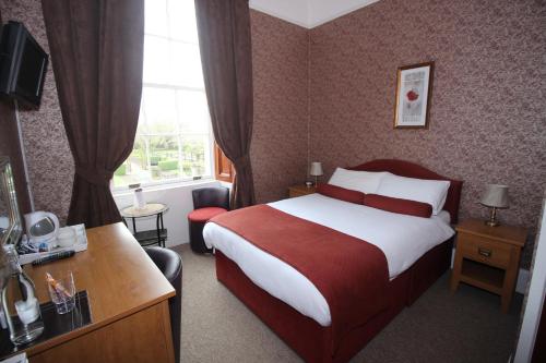 a hotel room with a bed and a desk and a window at The Southfield Hotel in Girvan