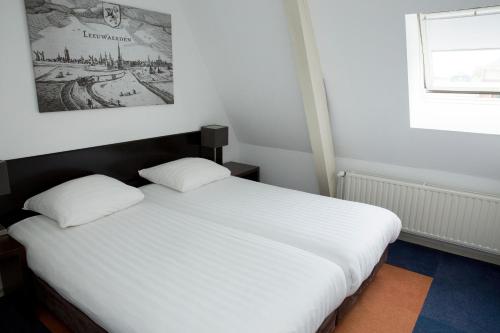 a white bed with two pillows in a room at Fletcher Hotel Paleis Stadhouderlijk Hof in Leeuwarden