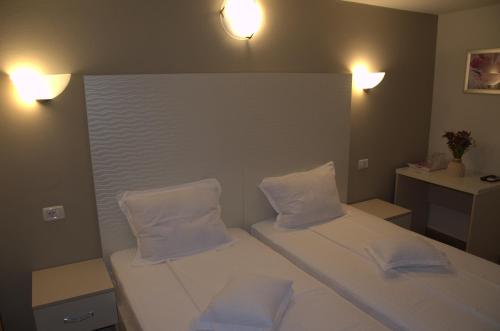 a bedroom with a bed with two pillows and two lights at Pensiune Xe-Mar in Arad