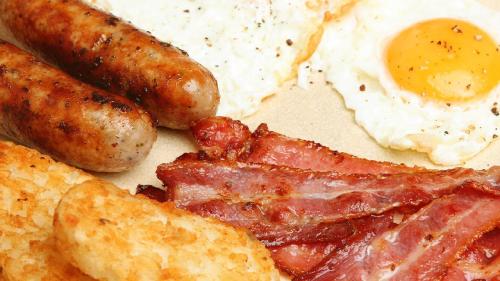 a plate of breakfast food with eggs sausage and bread at Elizabeth Hotel in Gyula