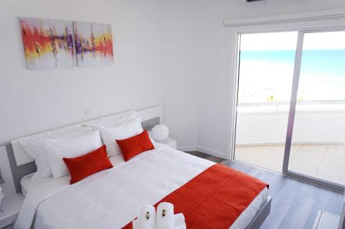 a bedroom with a large white bed with red pillows at Lazuli Sea View Beachfront Ap 43 in Larnaka
