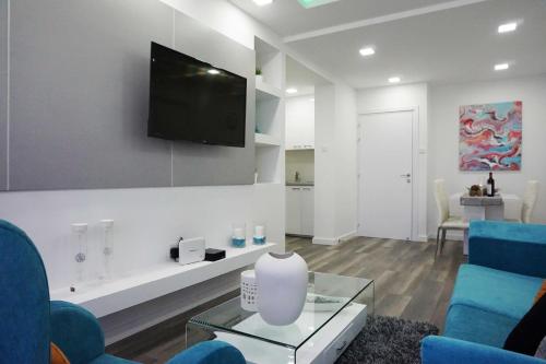a living room with blue chairs and a tv on the wall at Lazuli Sea View Beachfront Ap 43 in Larnaka