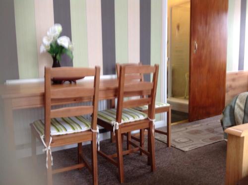 a dining room with two chairs and a wooden table at Sherwood Lodge in Skegness