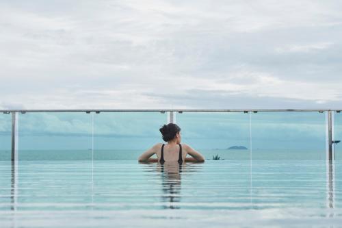 a woman sitting in the water in a infinity pool at Tribe Pattaya in Jomtien Beach