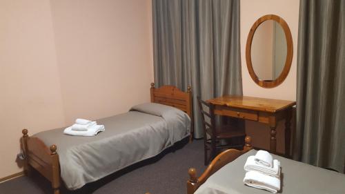 a room with two beds and a desk and a mirror at Hotel Calaluna in Biella