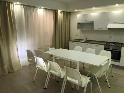 a kitchen with a white table and white chairs at Holiday home Isola Rossa in Isola Rossa